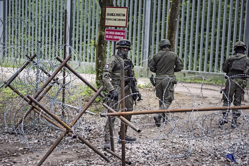 Två soldater som står bakom en barriär av taggtråd.